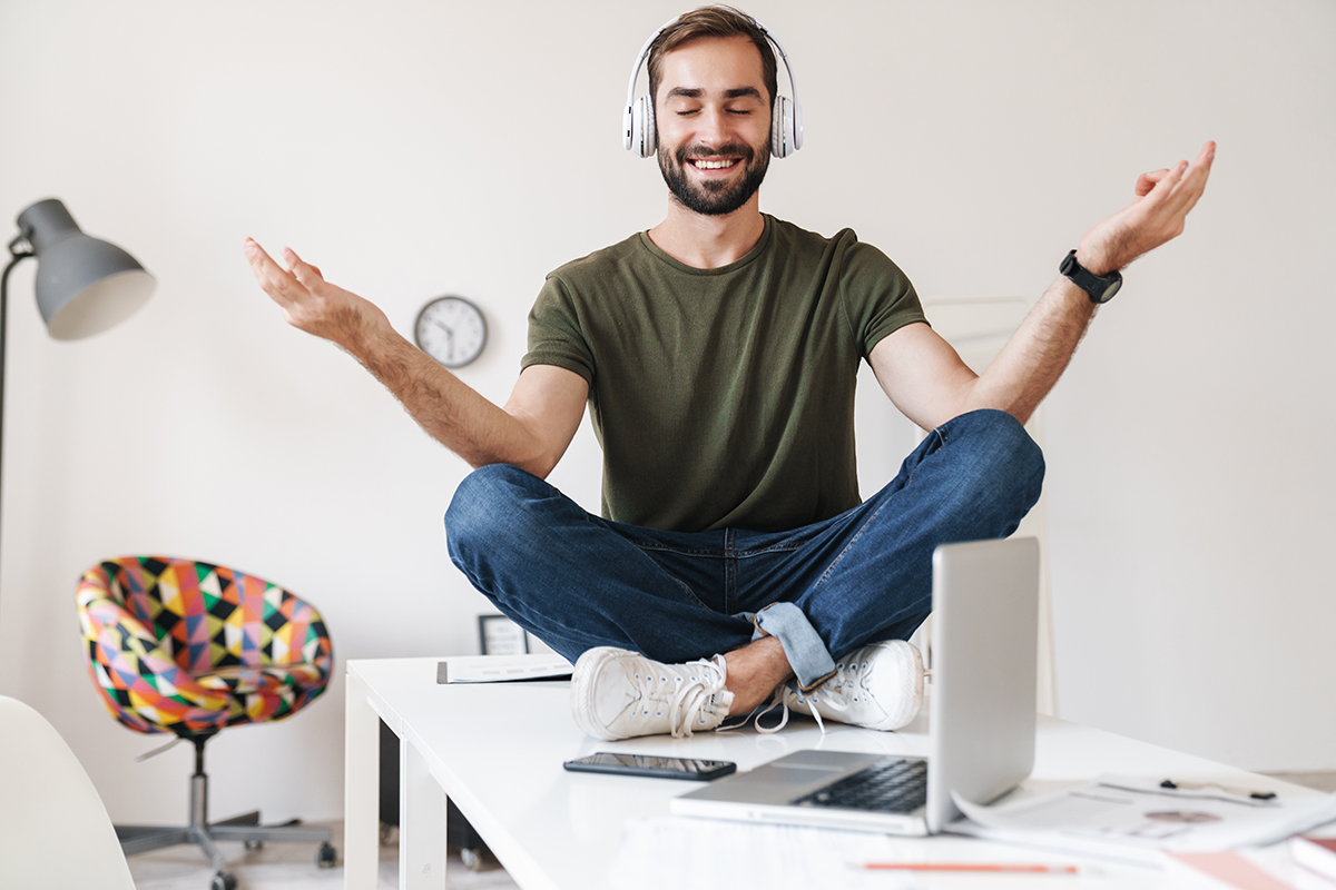 image of smiling man listening music with headphones while sitti